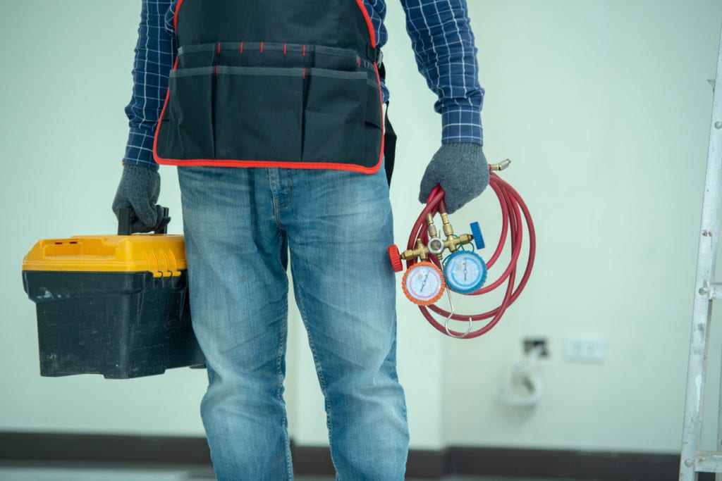 hvac-technician-holding-box-and-pressure-hoses